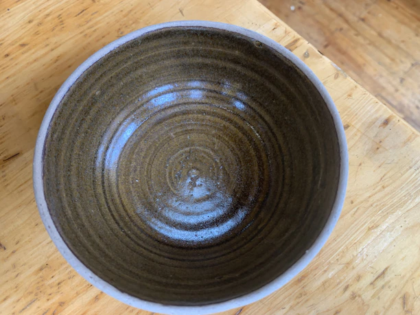 Close-up of a handcrafted ceramic bowl with bright, earthy tones and a smooth matte finish.