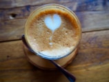Close-up of a creamy latte art heart in a ceramic mug on a wooden table.