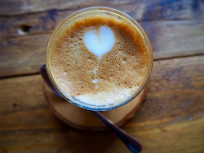 Close-up of a creamy latte art heart in a ceramic mug on a wooden table.