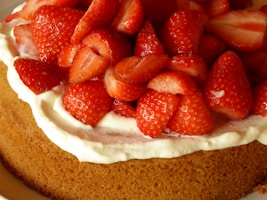Close-up of a creamy 18cm cake topped with fresh strawberries and delicate cream swirls