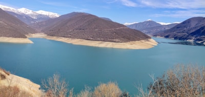 Sunlit view of a serene turquoise lake surrounded by high-altitude desert hills in Ladakh.