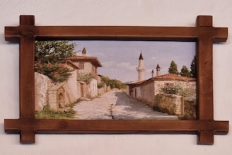 An old oil painting in a gilded frame depicting a serene European countryside scene.