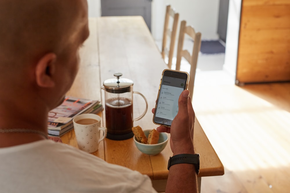 Un homme assis à une table tenant un téléphone intelligent