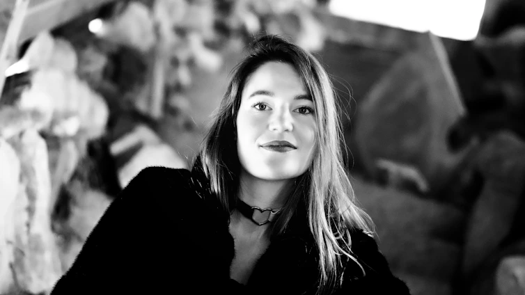 Professional portrait of Isis Delboni smiling warmly with a blurred city background.