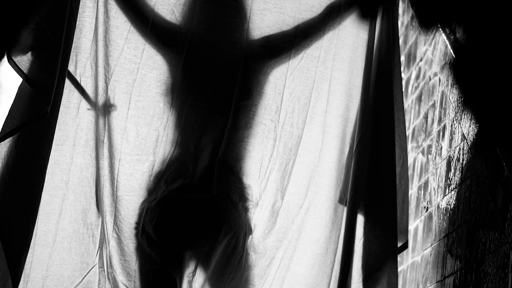 a shadow of a woman standing in front of a curtain