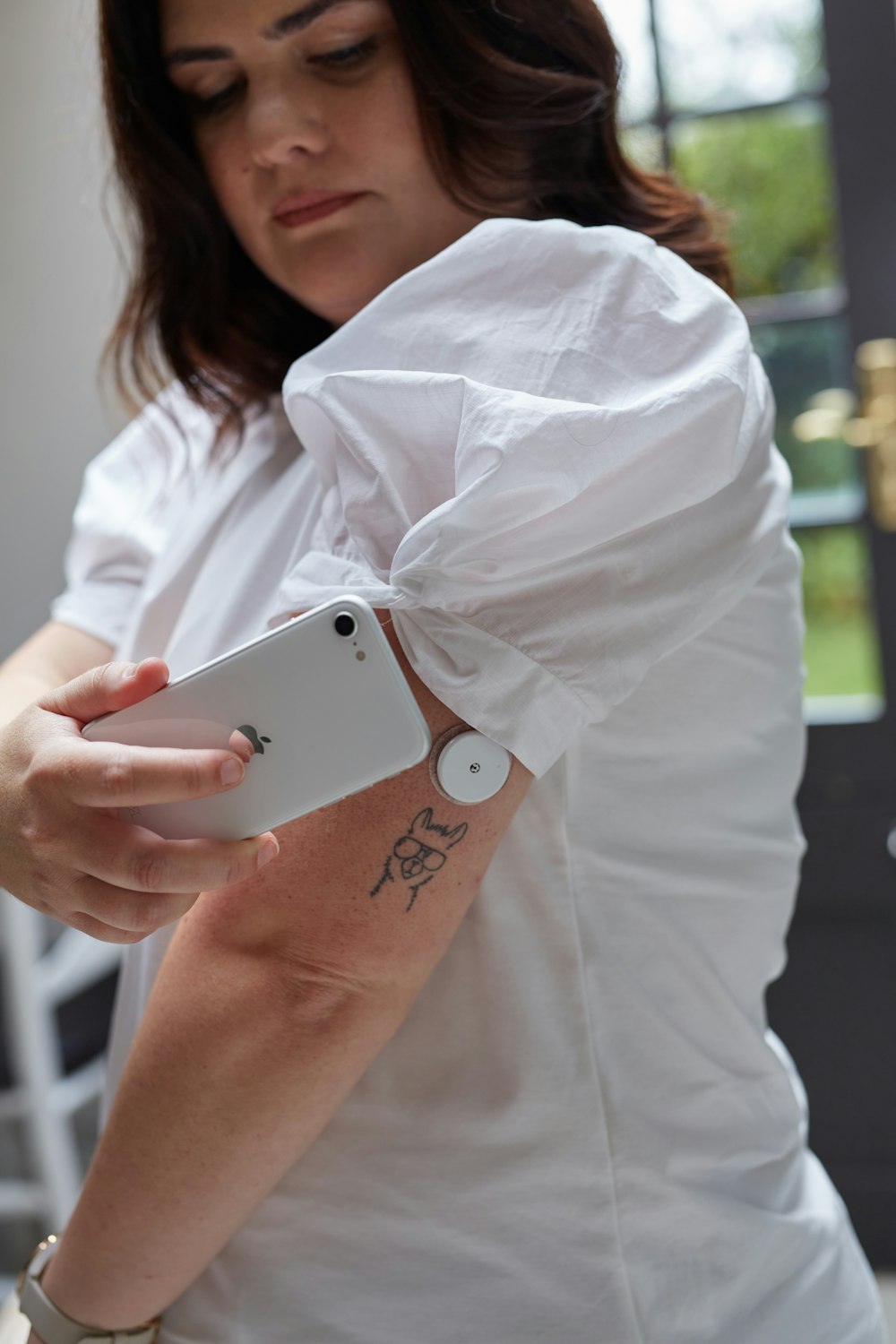 a woman holding a cell phone with a tattoo on her arm