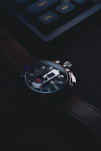 Close-up of hands adjusting a luxury watch strap with a bright red Lhosa Nepal logo in the background.