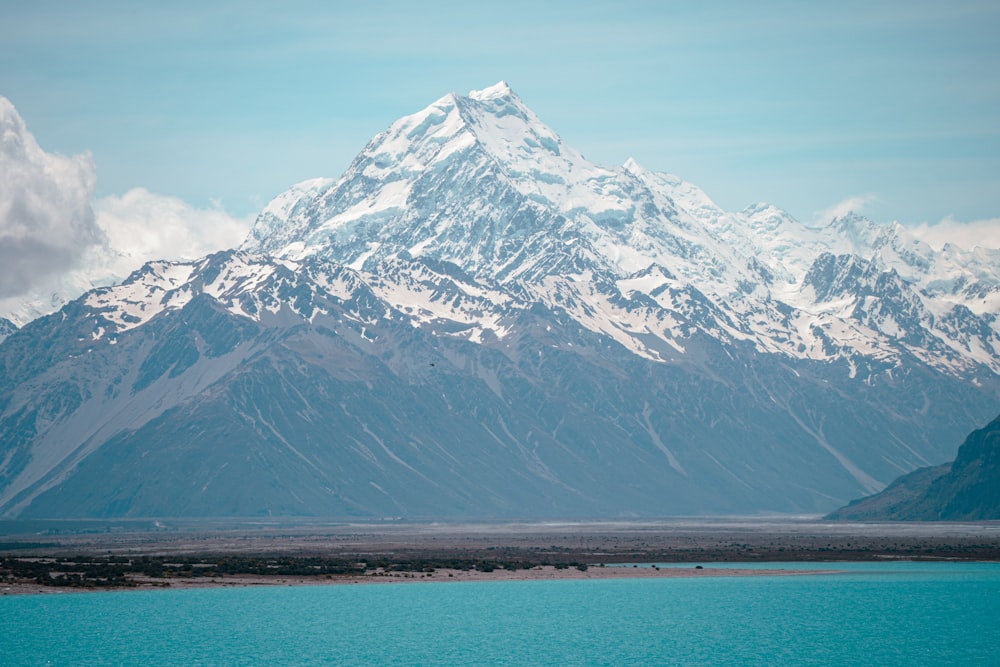 a large snow covered mountain towering over a body of water