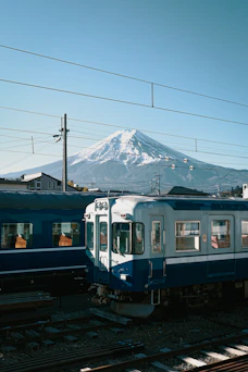 Blue trains on tracks before Mount Fuji in Fujinomiya, Japan