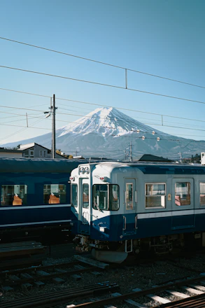 Blue and white train passing by snow-covered Mount Fuji landscape in winter Japan