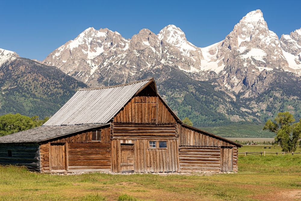 a barn in a field with mountains in the background