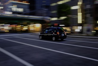 A modern taxi speeding through Kuwait city streets at sunset.