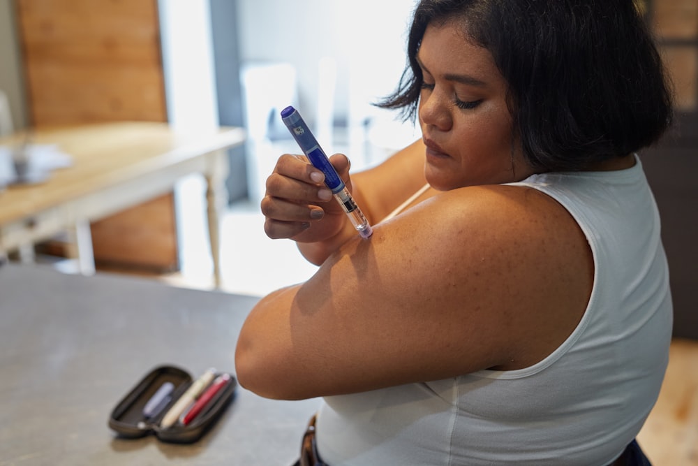 Una mujer sosteniendo un bolígrafo y un teléfono celular