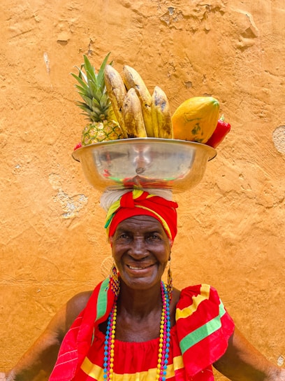 An inspiring, bright photo of an elderly man smiling while holding a basket filled with fresh vegetables, radiating health and happiness.