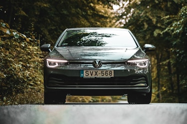 a car driving down a road next to a forest