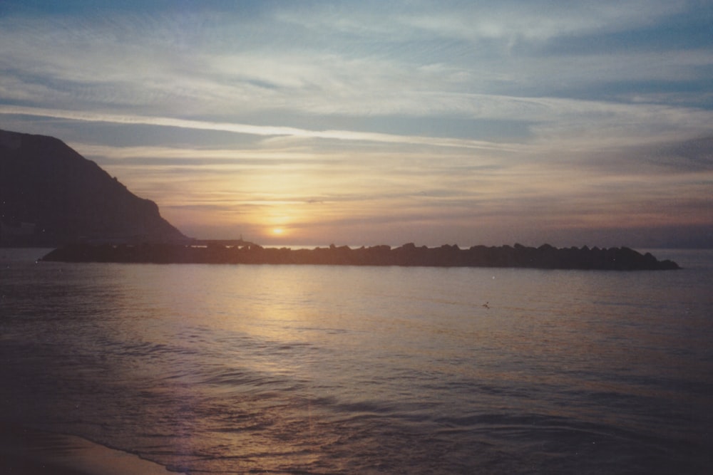 the sun is setting over a small island in the ocean