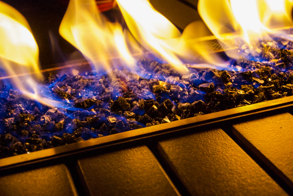 Close up of blue and yellow gas flames dancing over a bed of glass beads in a modern gas fire