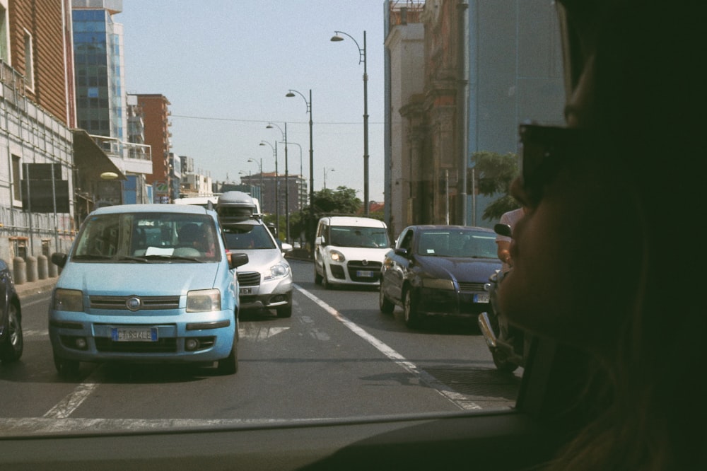 a blue car driving down a street next to tall buildings