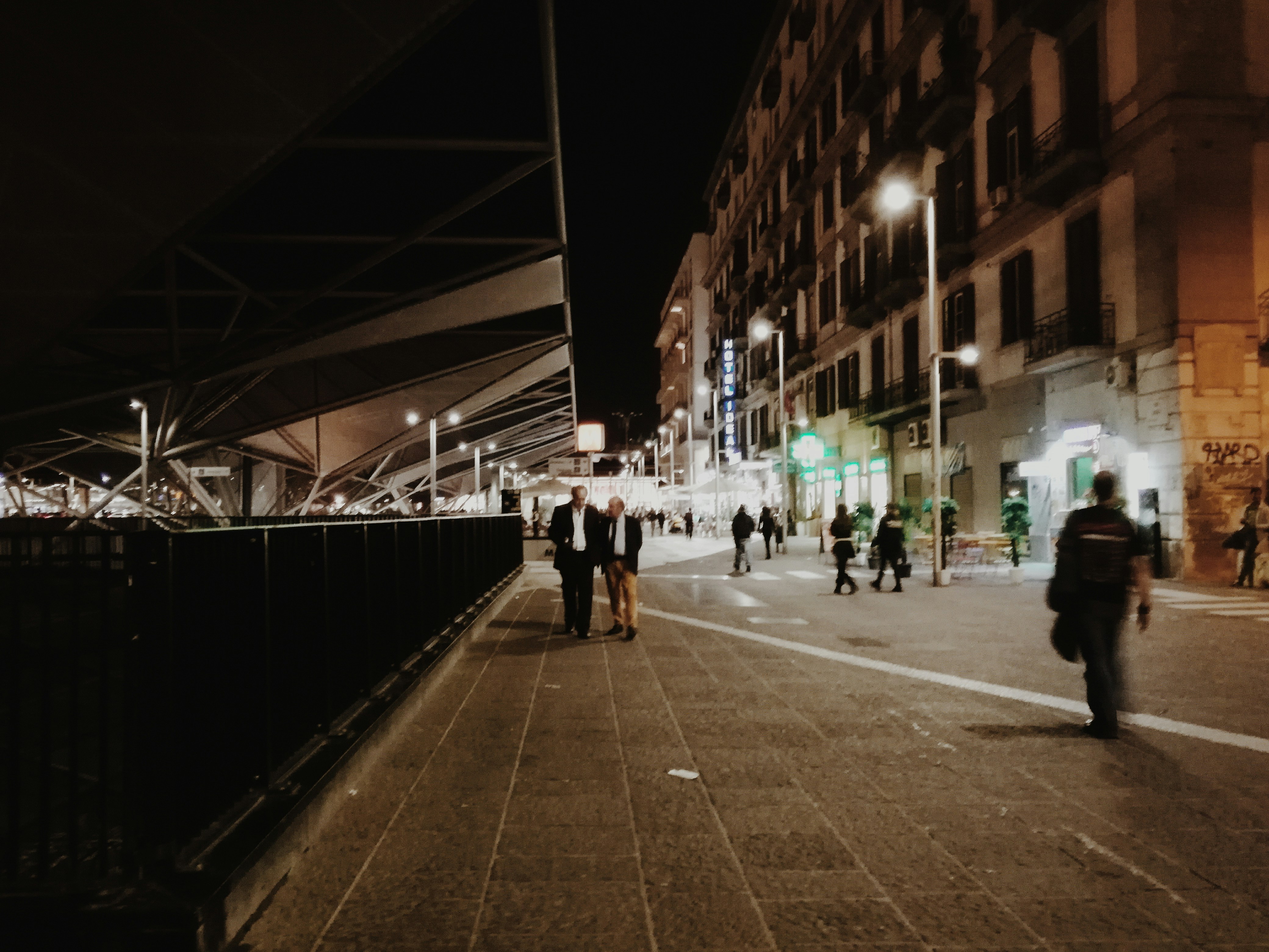 a group of people walking down a street at night