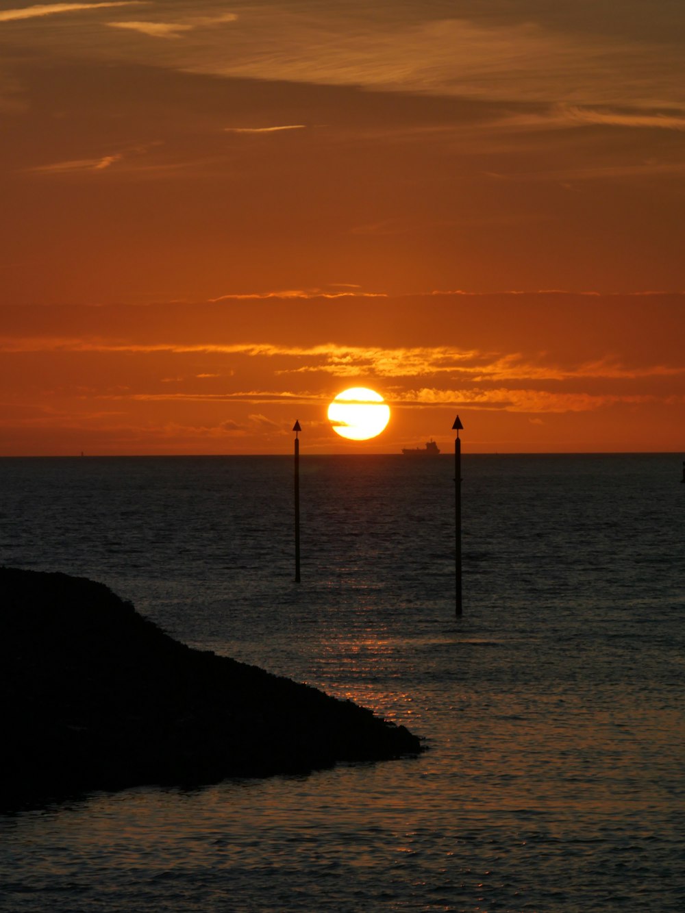 El sol se está poniendo sobre el océano con un faro en primer plano