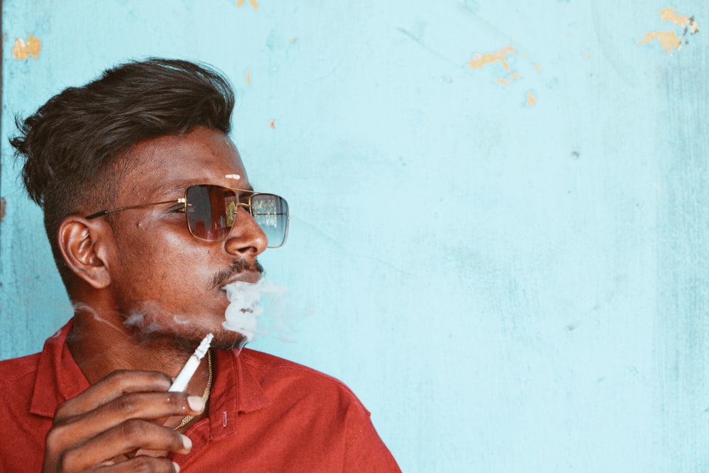 a man in a red shirt smoking a cigarette