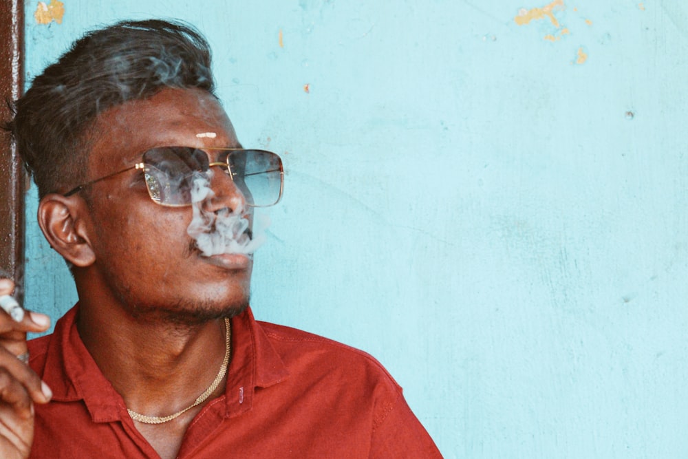 a man in a red shirt smoking a cigarette