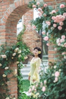 A serene portrait of a woman in a pastel cotton suit standing by a blooming jasmine bush.