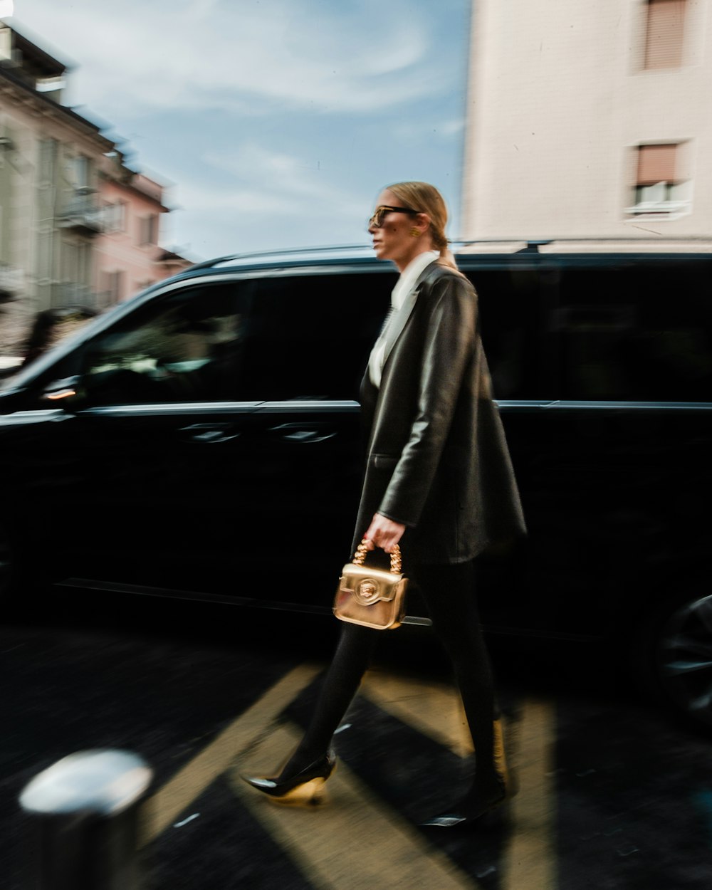 a woman walking across a street holding a purse