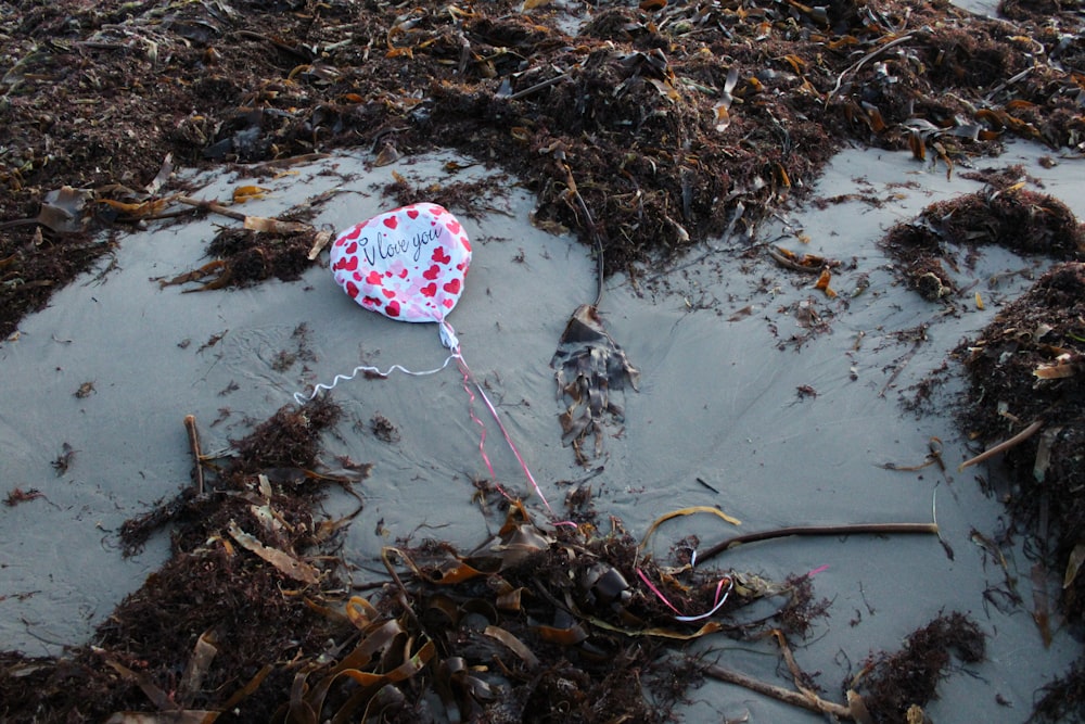 a heart shaped kite laying on top of a sandy beach