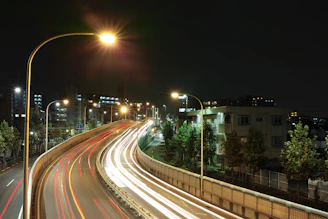 Nighttime shot of a SwiftTrack semi illuminated by red taillights heading down a highway, city lights in the distance