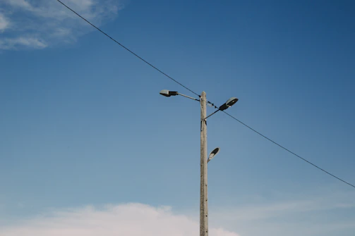 Concrete utility poles standing tall along a busy street in Brasília under a clear blue sky.