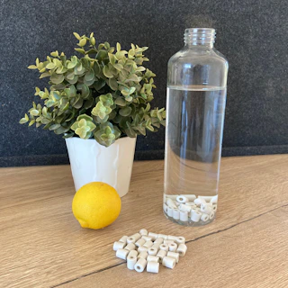 Fresh green leaves next to a bottle filled with alkaline water, symbolizing health.