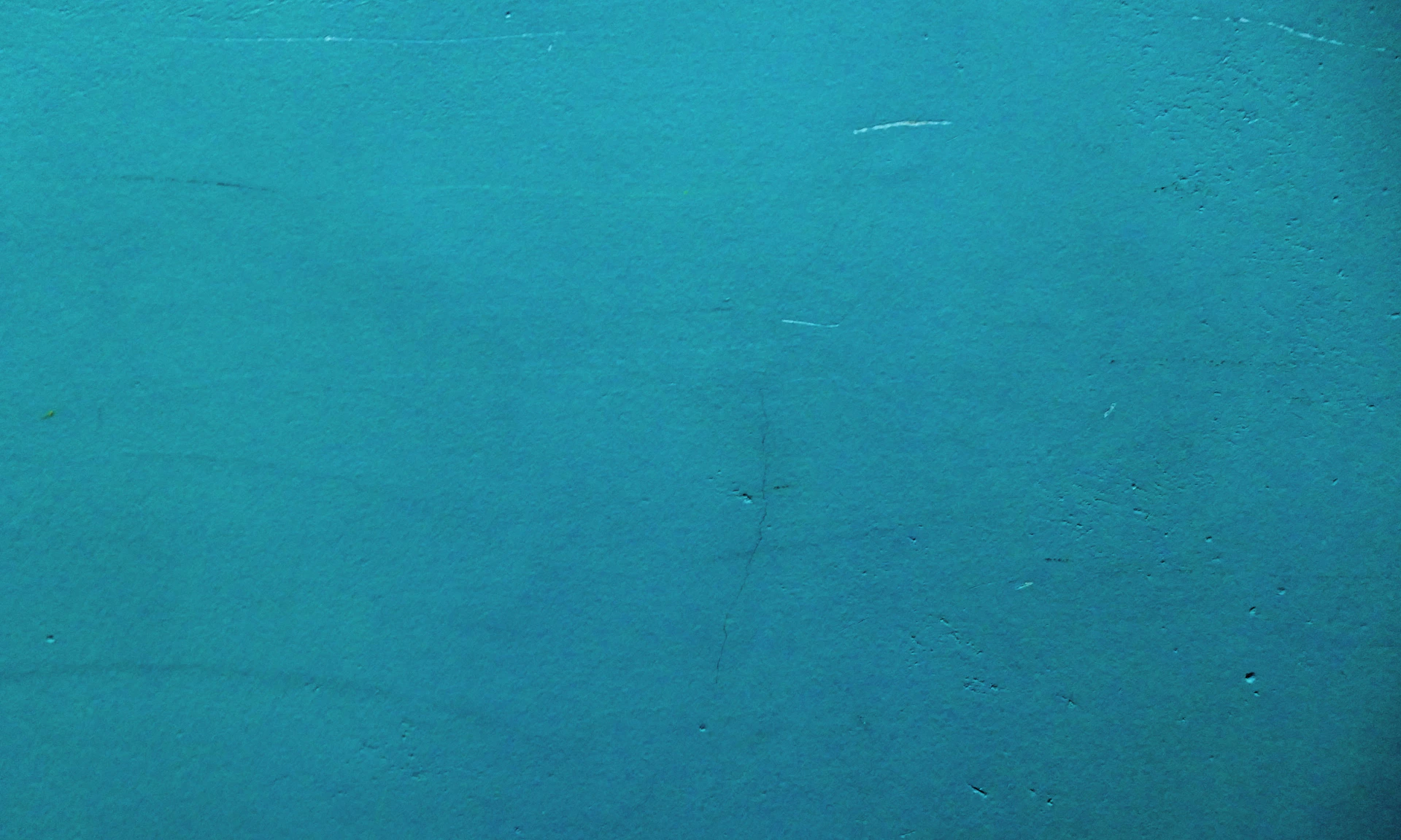 a red fire hydrant sitting on the side of a blue wall