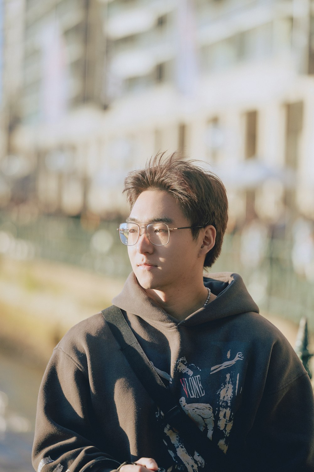 a man wearing glasses standing in front of a building