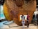 A large, translucent honeycomb structure dominates the scene, with two children interacting with a digital screen integrated into it. The honeycomb is composed of numerous hexagonal cells and is surrounded by a modern indoor environment.