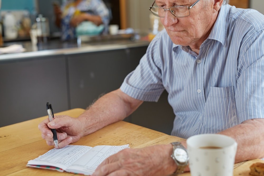 a man sitting at a table writing on a piece of paper