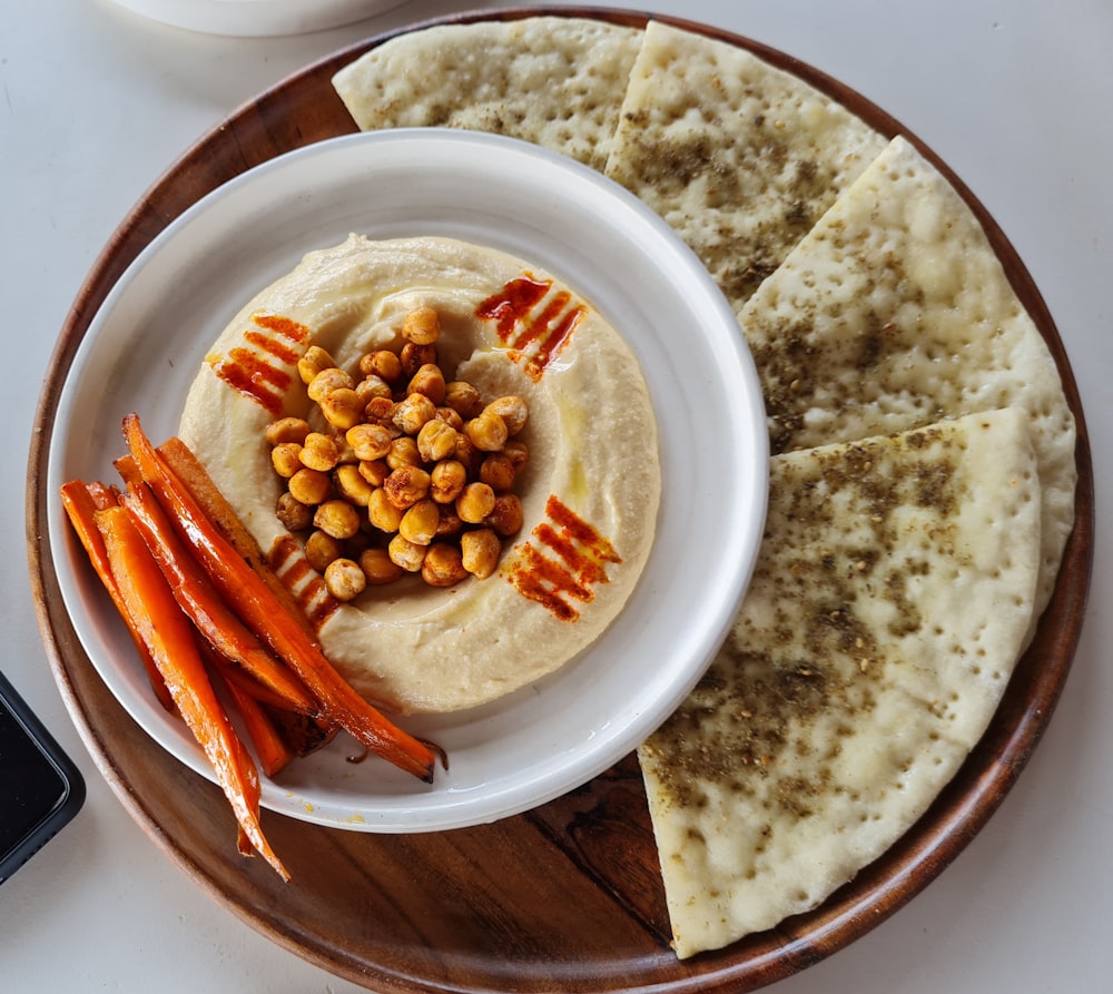 a plate of hummus, carrots, and pita bread