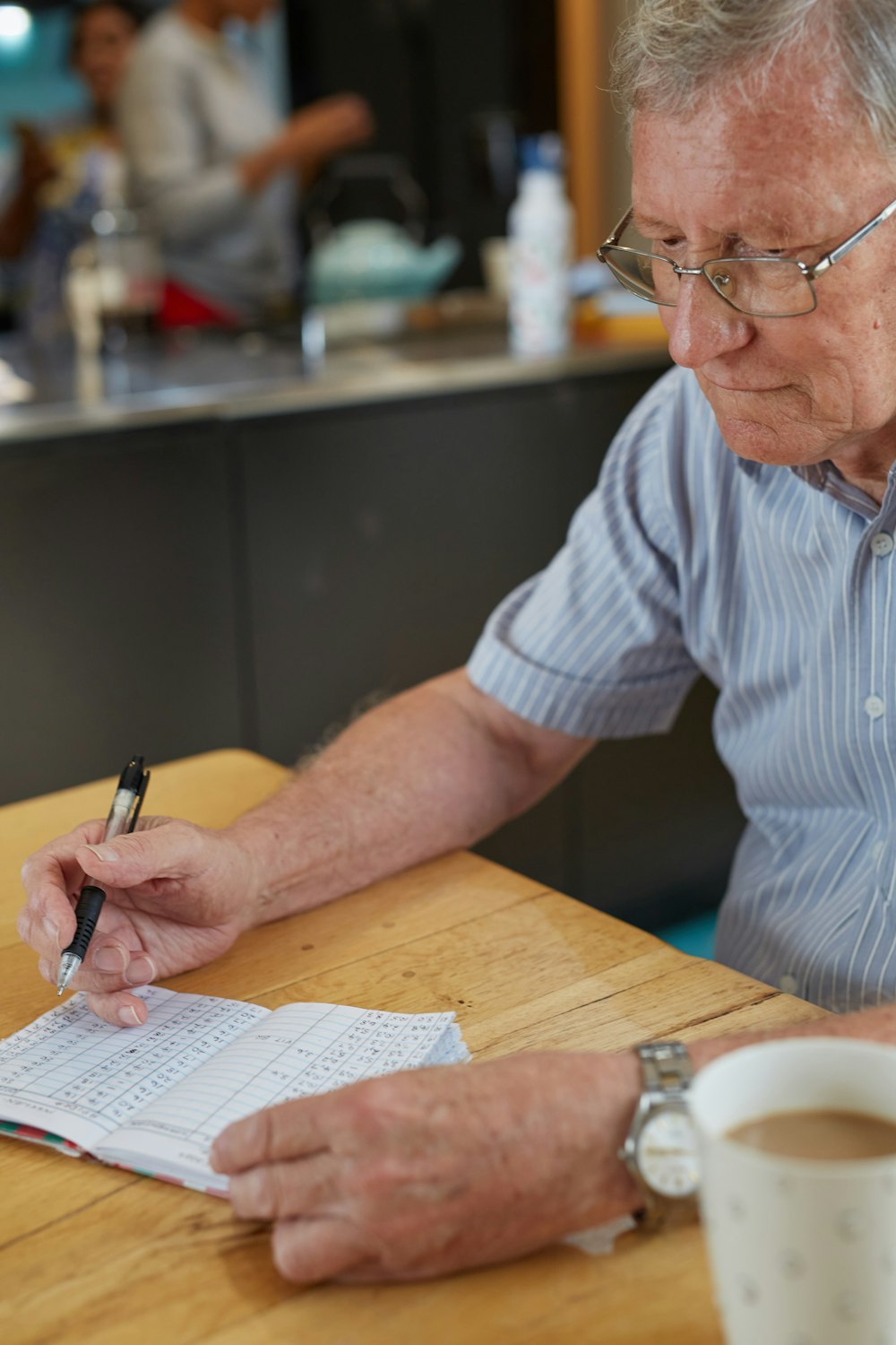 a man sitting at a table writing on a piece of paper