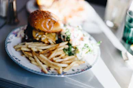 A vibrant plate with a gourmet burger, crispy fries, and a side salad.