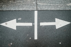 two white arrows pointing in opposite directions on asphalt