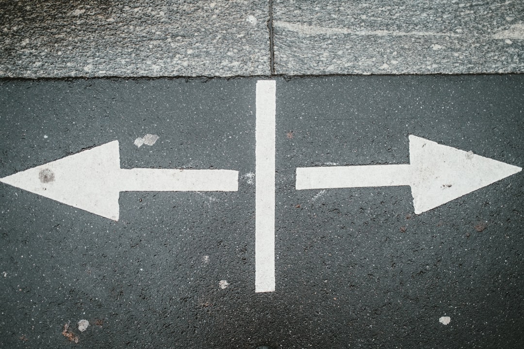 two white arrows pointing in opposite directions on asphalt