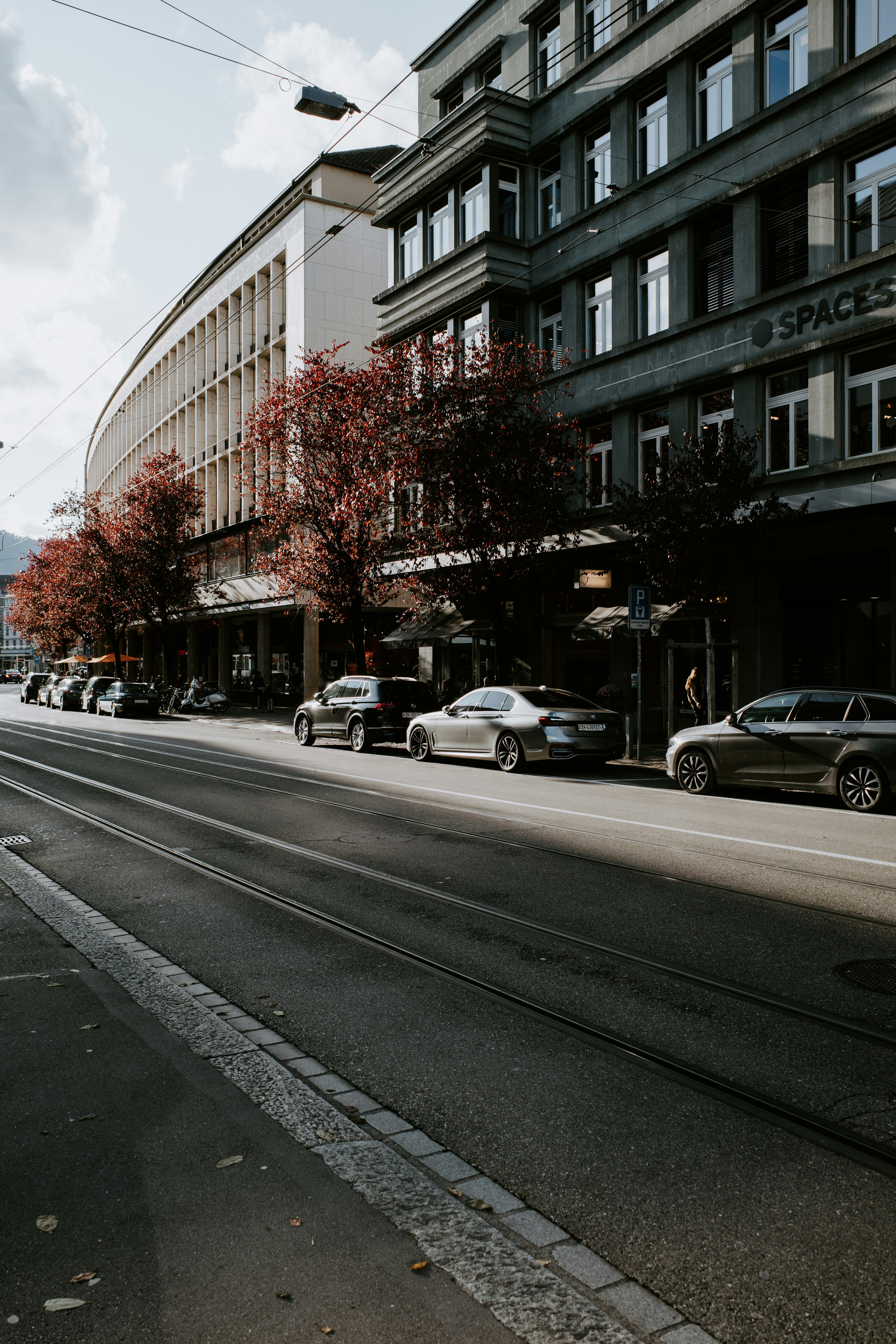 Eine Stadtstraße, gesäumt von geparkten Autos und hohen Gebäuden