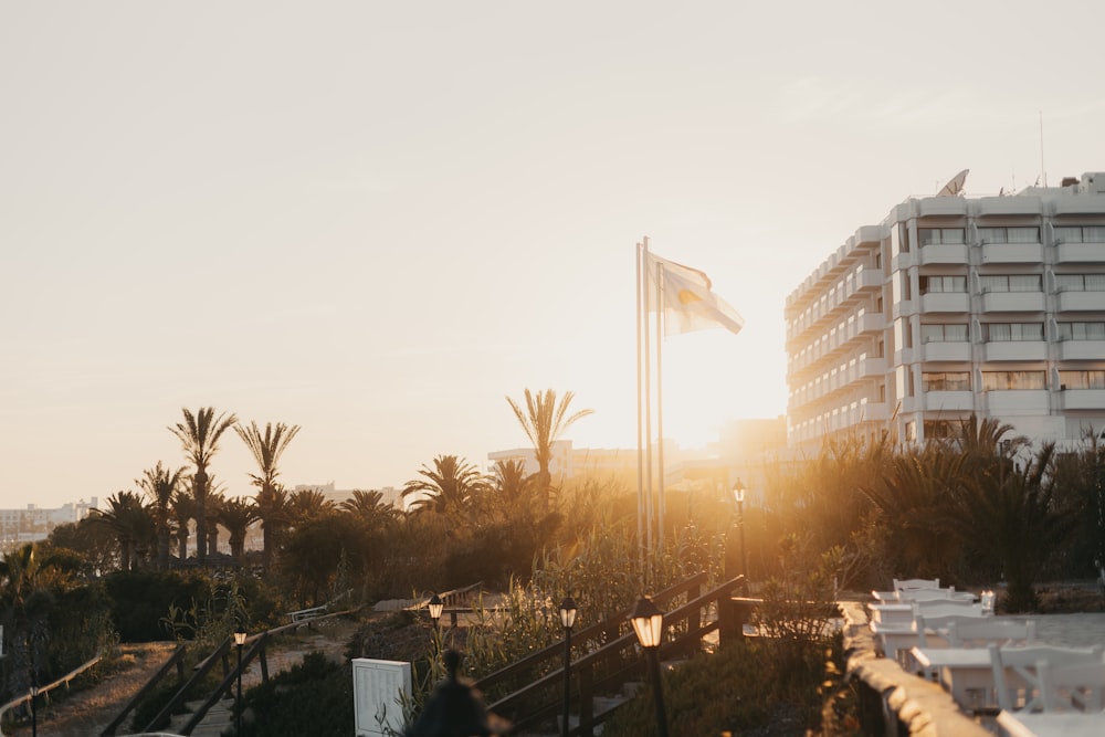 the sun is setting behind a building with palm trees