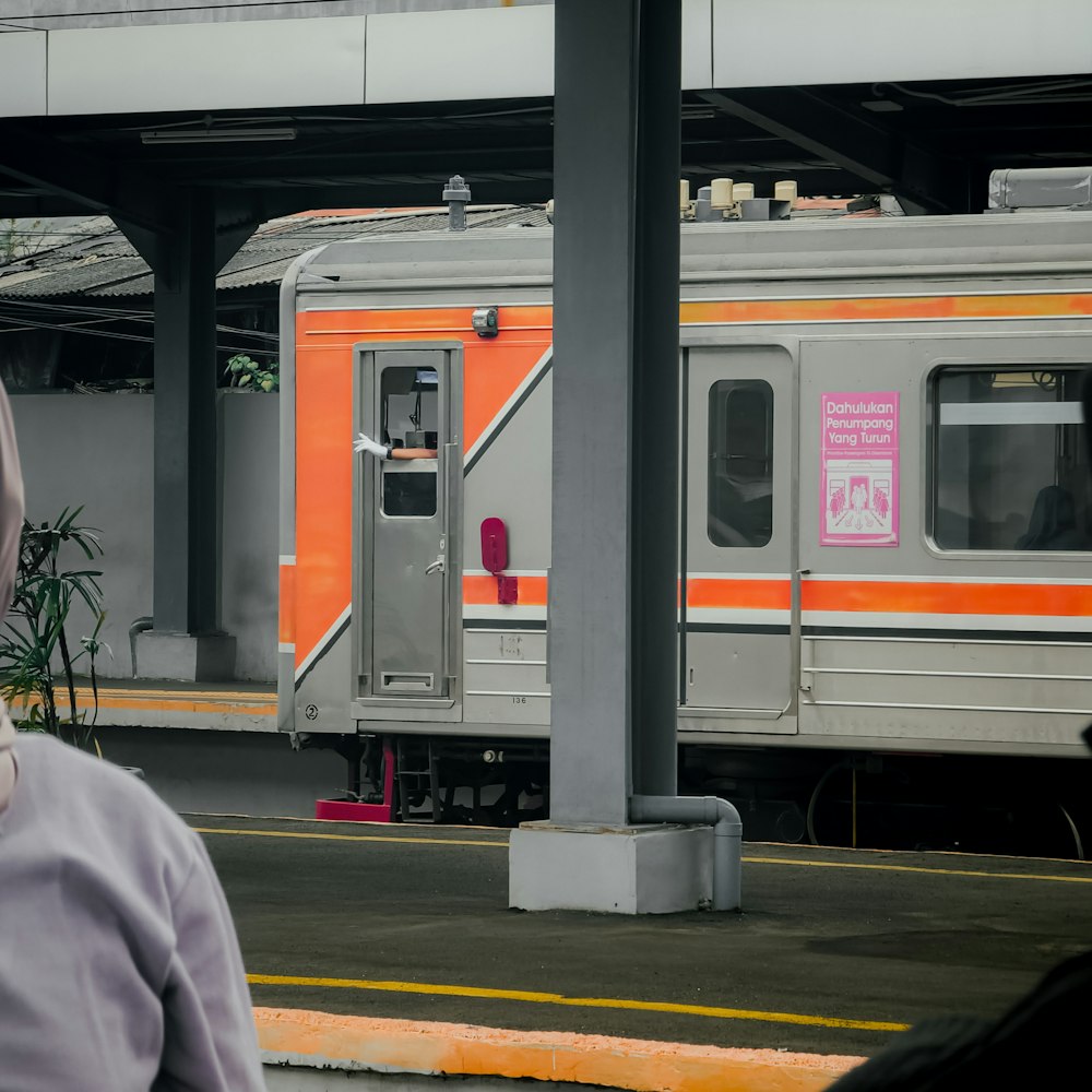 an orange and silver train at a train station