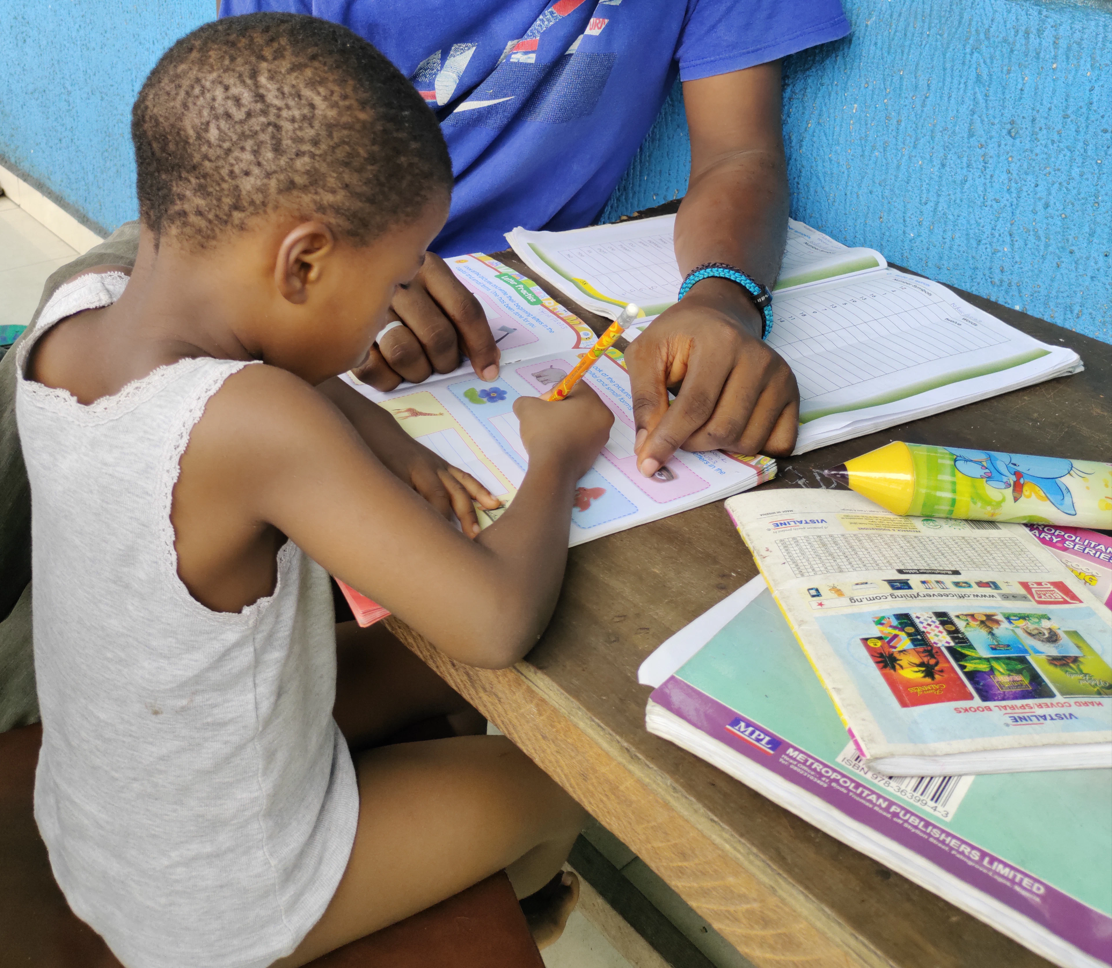 A young boy at a table with a book and pencil