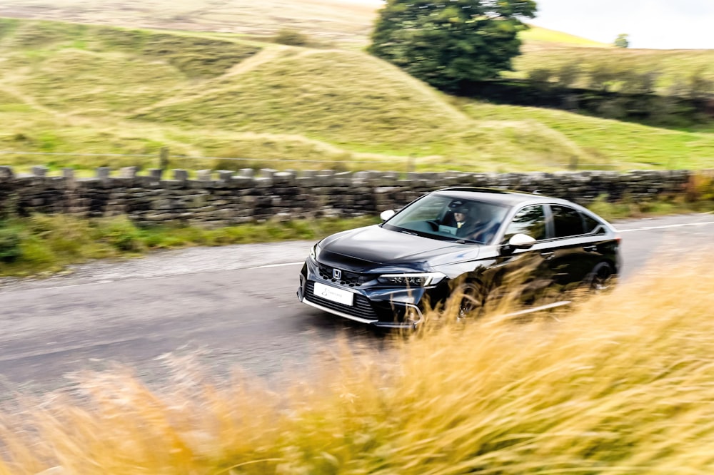 a black car driving down a country road