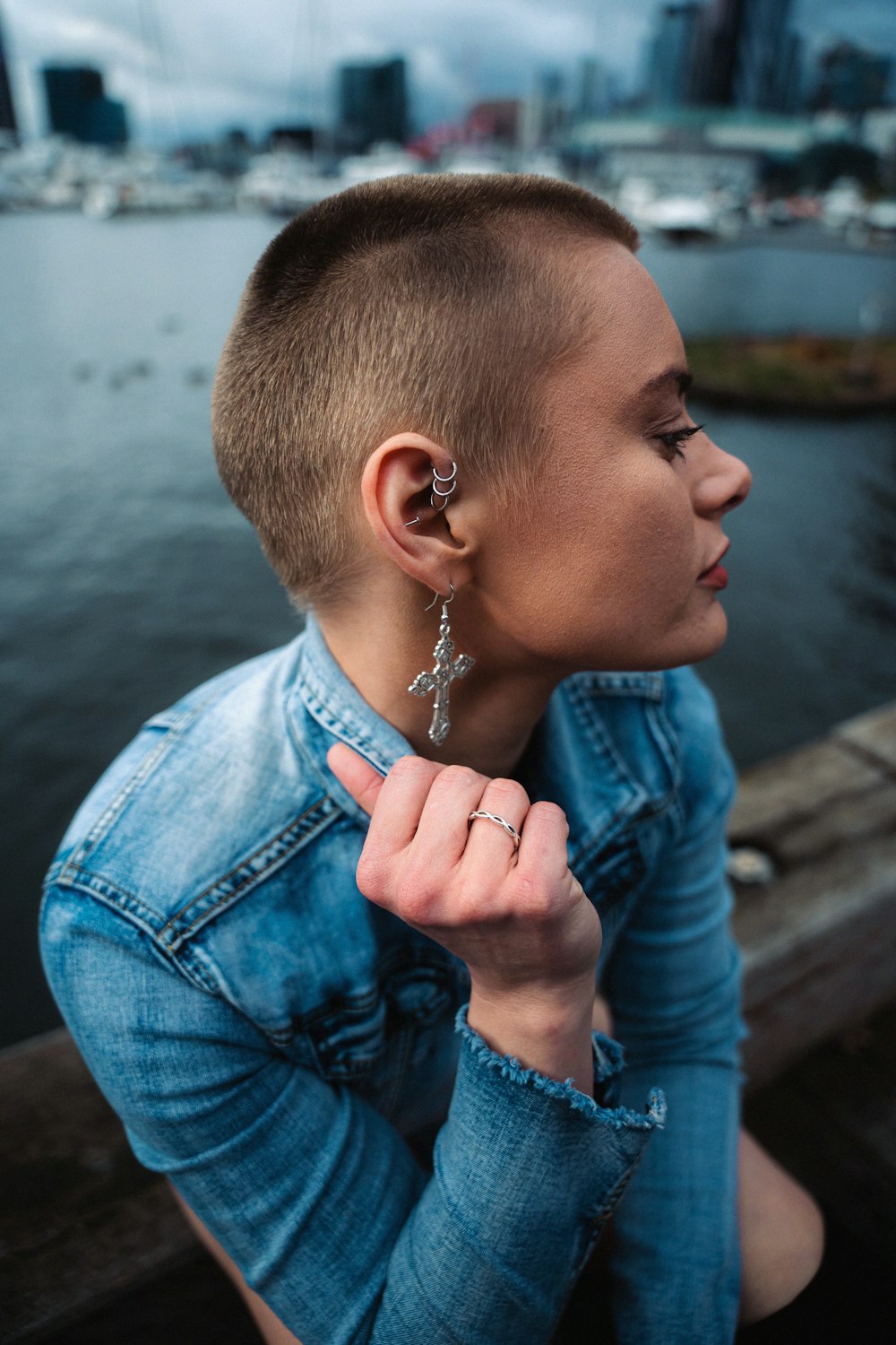 a woman with a shaved head wearing a denim jacket