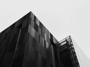 A sleek, modern architectural building with sharp lines and dramatic lighting in dark mode.