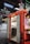 A red food truck with open doors reveals a stainless steel interior, including a sink and shelving. Above, a blue sign reads 'Sägecenter' inside a large industrial warehouse with visible steel beams and pipes. On the right side of the truck, a poster with vivid graphics adds a pop of color.