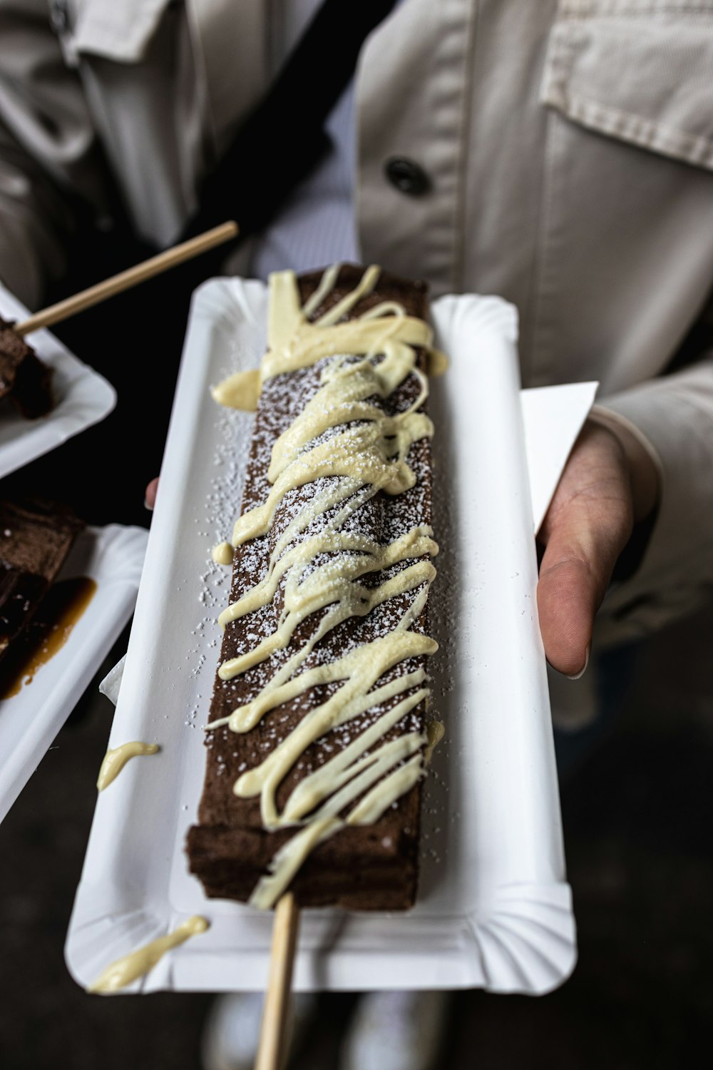 a person holding a plate with a chocolate dessert on it